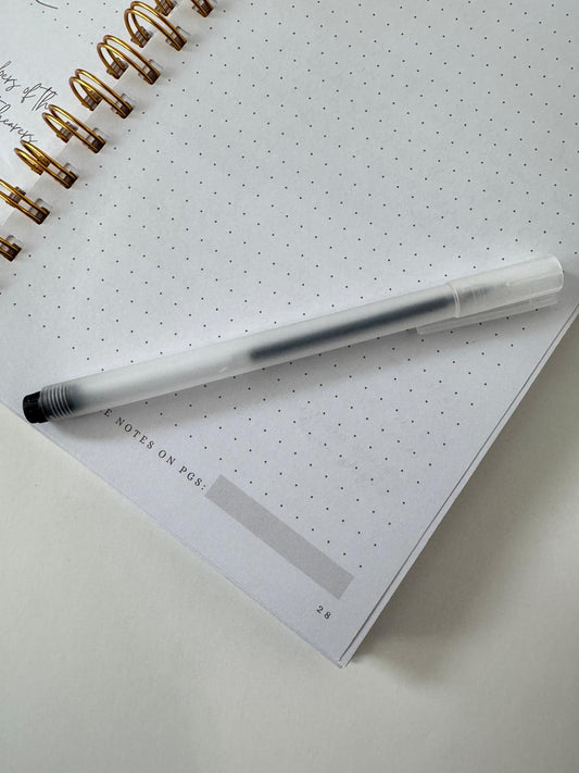 Clear barrel gel pen on journal